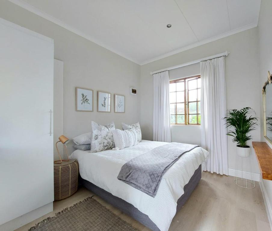 a white bedroom with a large bed and a window at Upmarket off grid cottage on organic farm in secure estate in Howick
