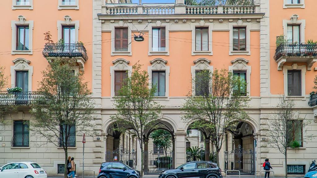 un grand bâtiment avec des voitures garées devant lui dans l'établissement Sant'Ambrogio Suite Apartment, à Milan