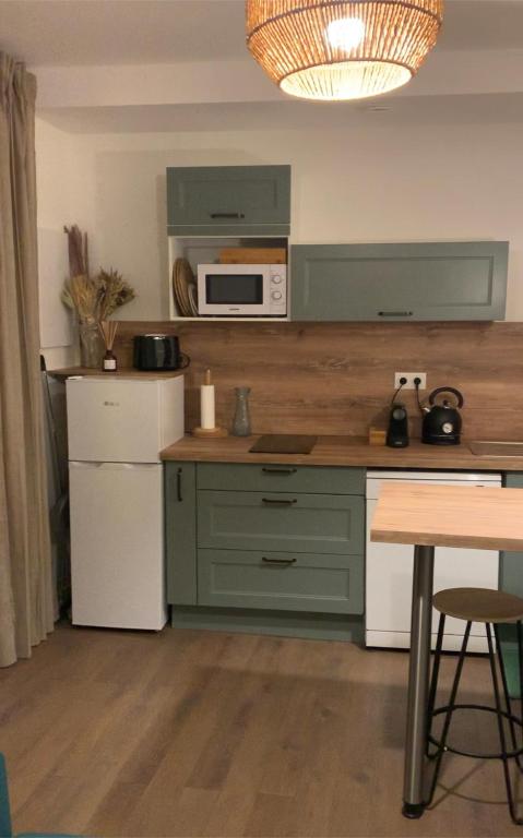 a kitchen with green cabinets and a white microwave at Le relais appartement aux charmes authentiques WIFI in Périgueux