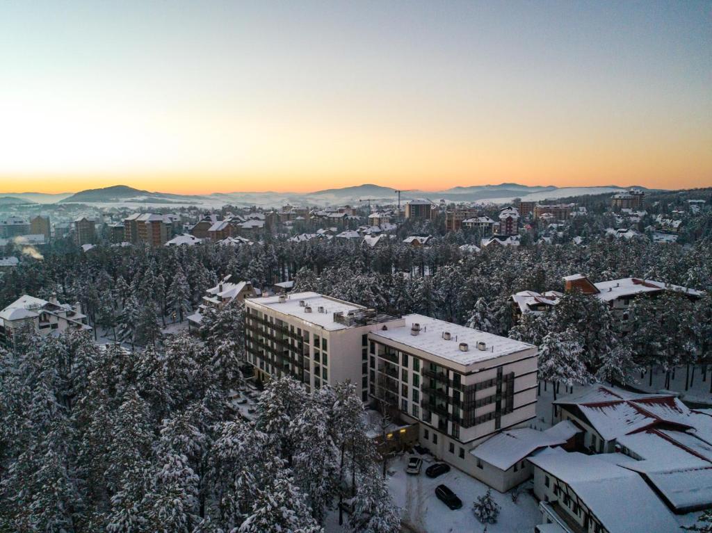 een stad met sneeuw bedekte bomen en een gebouw bij Hotel Palisad in Zlatibor
