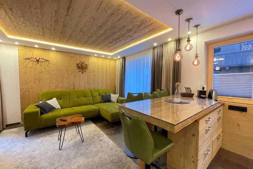 a living room with a green couch and a table at Quality Hosts Arlberg - ALPtyrol Appartements in Sankt Anton am Arlberg