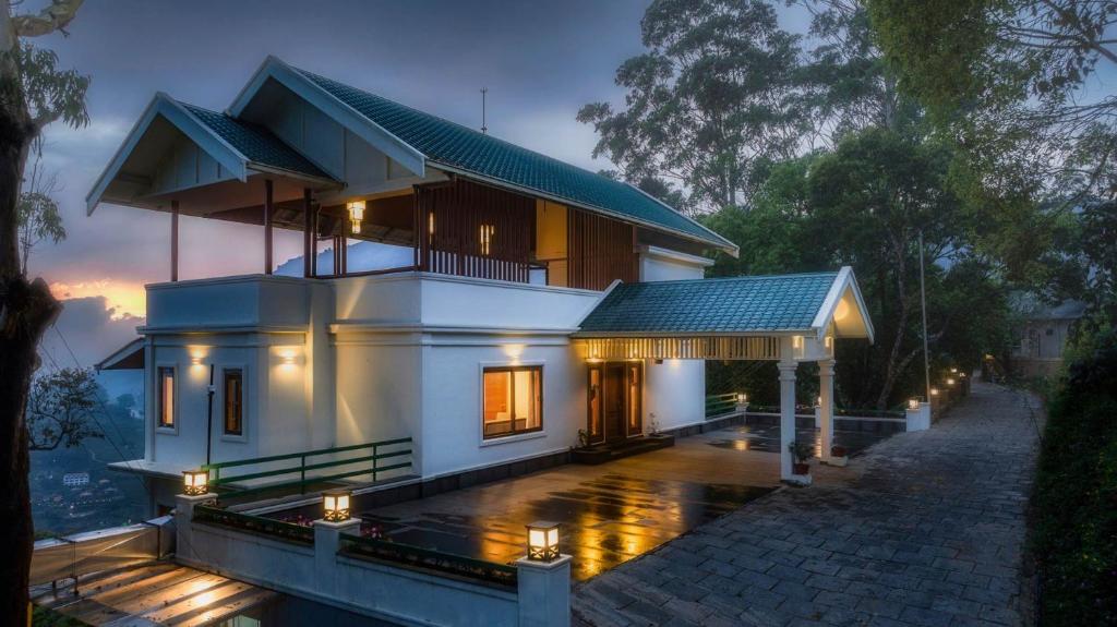 una casa blanca con luces delante en StayVista at Paradise Valley View with Terrace Access, en Munnar