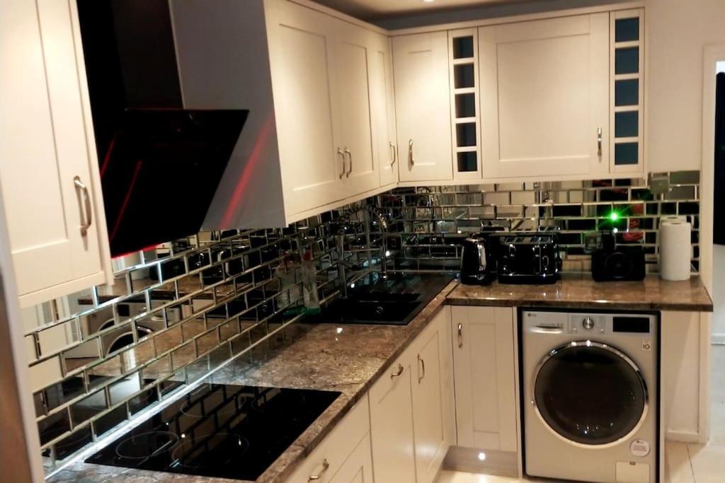 a kitchen with white cabinets and a washer and dryer at Impeccable 2-Bed House in London