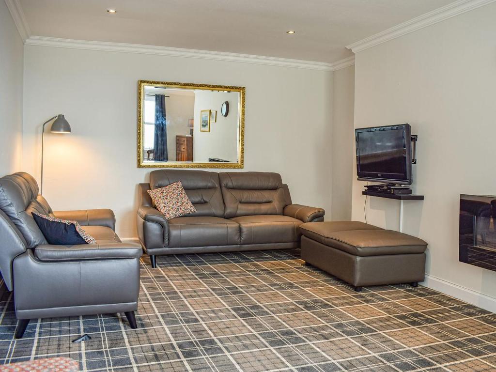 a living room with a leather couch and a television at Sea View in Anstruther