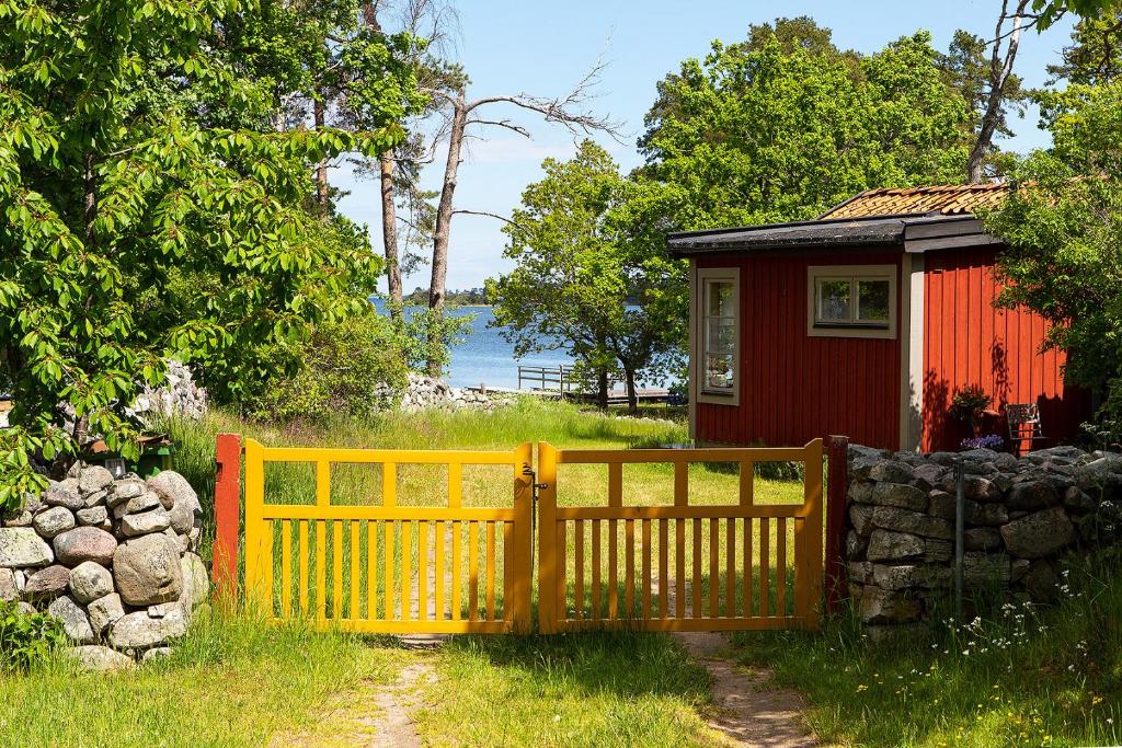 una cerca amarilla frente a una casa pequeña en Holiday house in Drag with a unique location and lake plot, en Rockneby