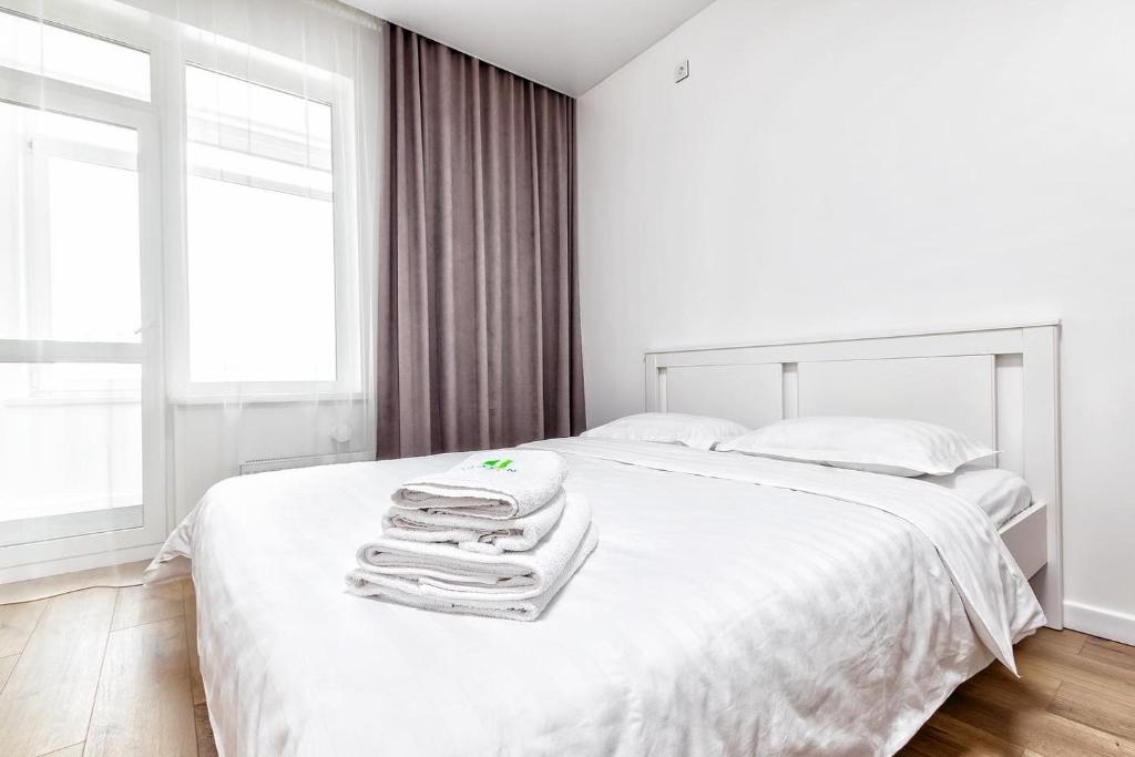 una camera da letto bianca con un letto e asciugamani di Raisson Ahotel GT79 a Astana