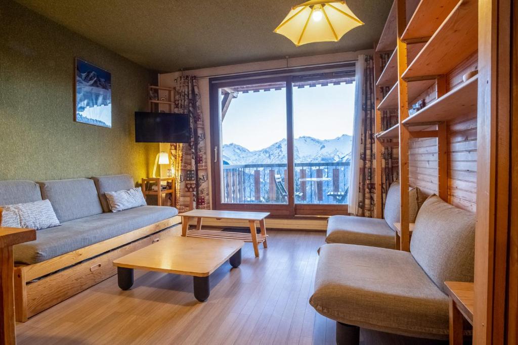 a living room with a couch and a large window at Welcoming apartment in the Alpe d'Huez - Welkeys in LʼHuez