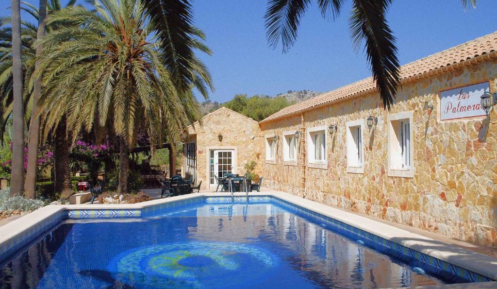 a swimming pool in front of a building with palm trees at Fonda Las Palmeras in Font de Sa Cala