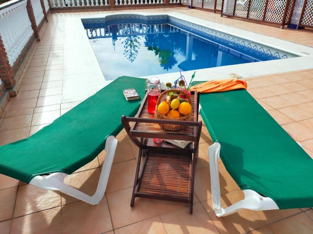een tafel met een fruitmand naast een zwembad bij Villa Azahar Anita in Nerja