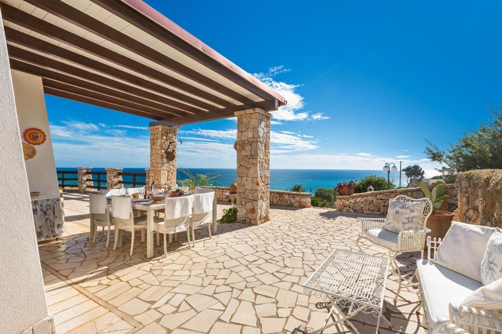 een patio met een tafel en stoelen en de oceaan bij Villa Carmen by Perle di Puglia in Morciano di Leuca