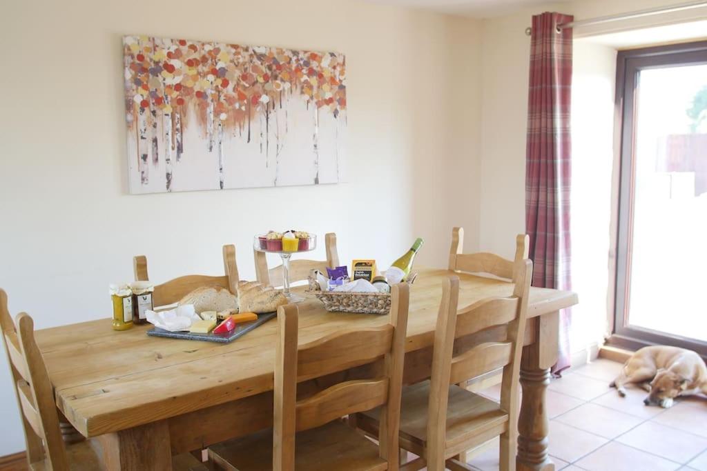 a wooden dining room table with a dog laying on the floor at Beautiful 4 Bedroom Cottage - Cottage 4 in Doncaster