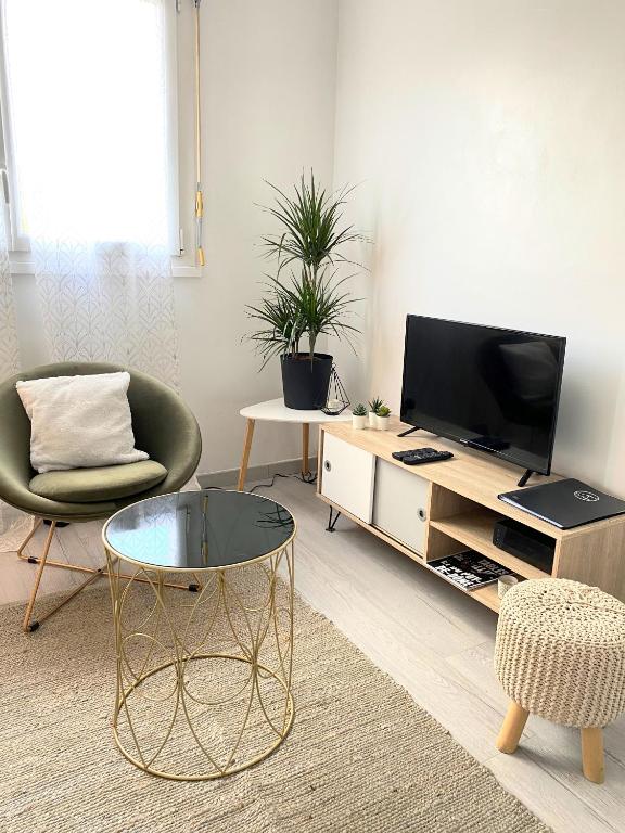 a living room with a tv and a chair and a table at COSY in Clermont-Ferrand