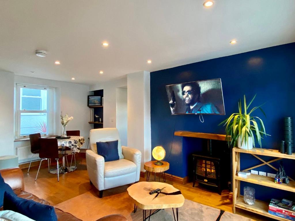 a living room with a blue accent wall at Extended Fishermans cottage with stunning sea views in The Mumbles