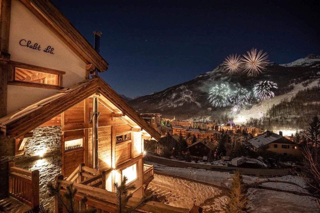 a log cabin with a mountain in the background at night at Luxury chalet Léli in Saint-Chaffrey