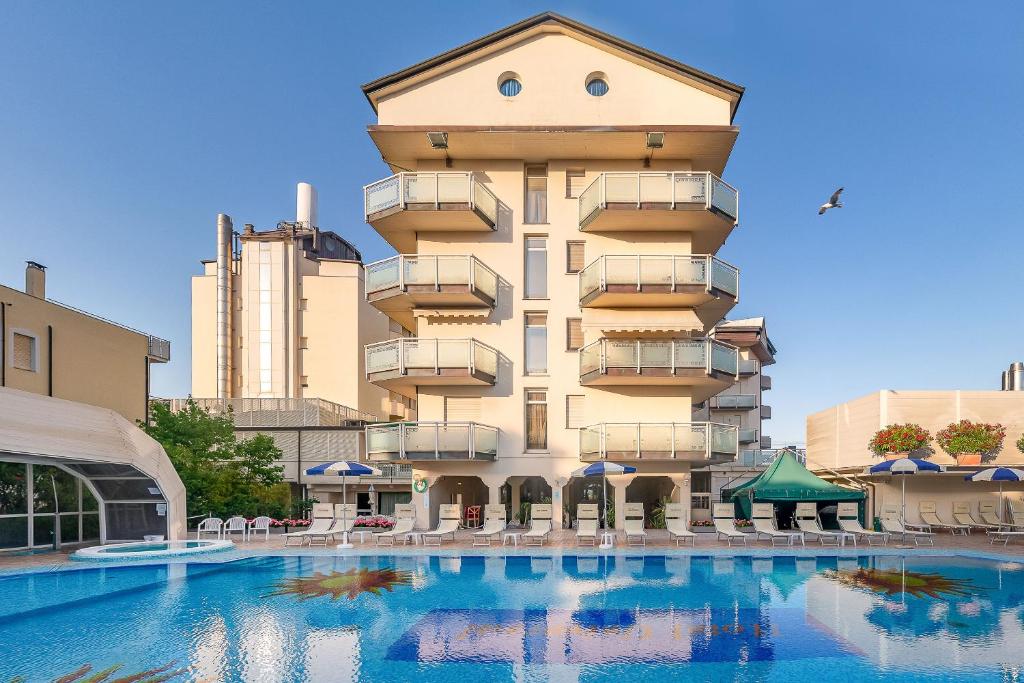 un hôtel avec une piscine en face d'un bâtiment dans l'établissement Universal Hotel, à Cervia