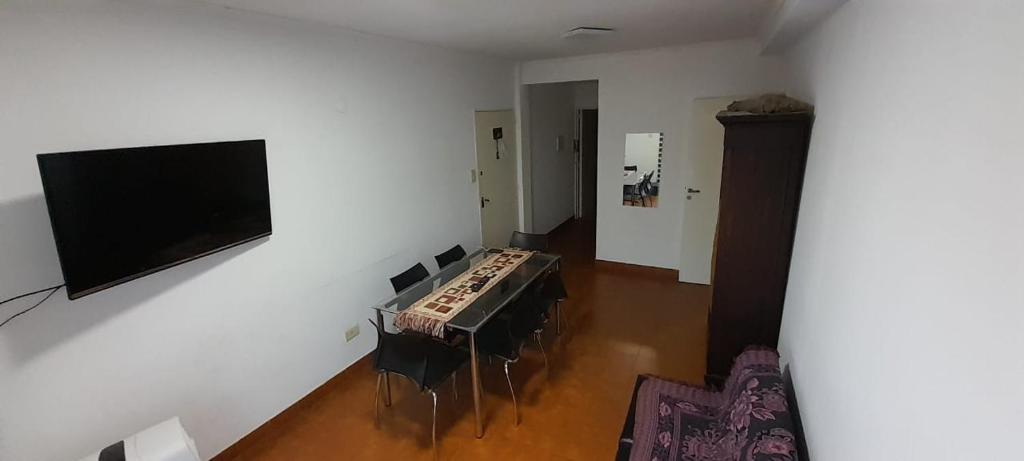 sala de estar con mesa, sillas y TV de pantalla plana. en Departamento Malvinas en Corrientes