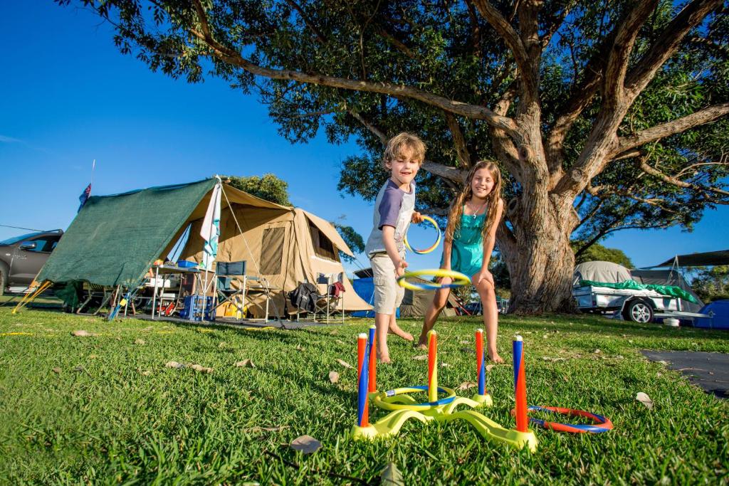 a boy and a girl playing with a toy in the grass at Reflections Hawks Nest - Holiday Park in Hawks Nest