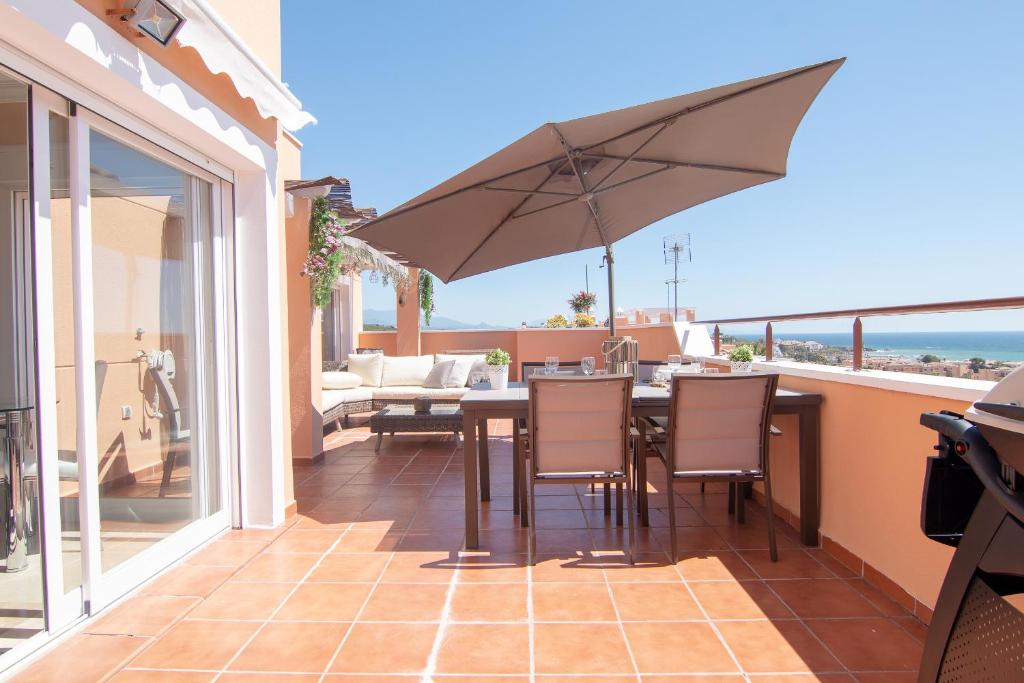 eine Terrasse mit einem Tisch und einem Sonnenschirm in der Unterkunft 2242-amazing penthouse 2terraces sea view in Casares