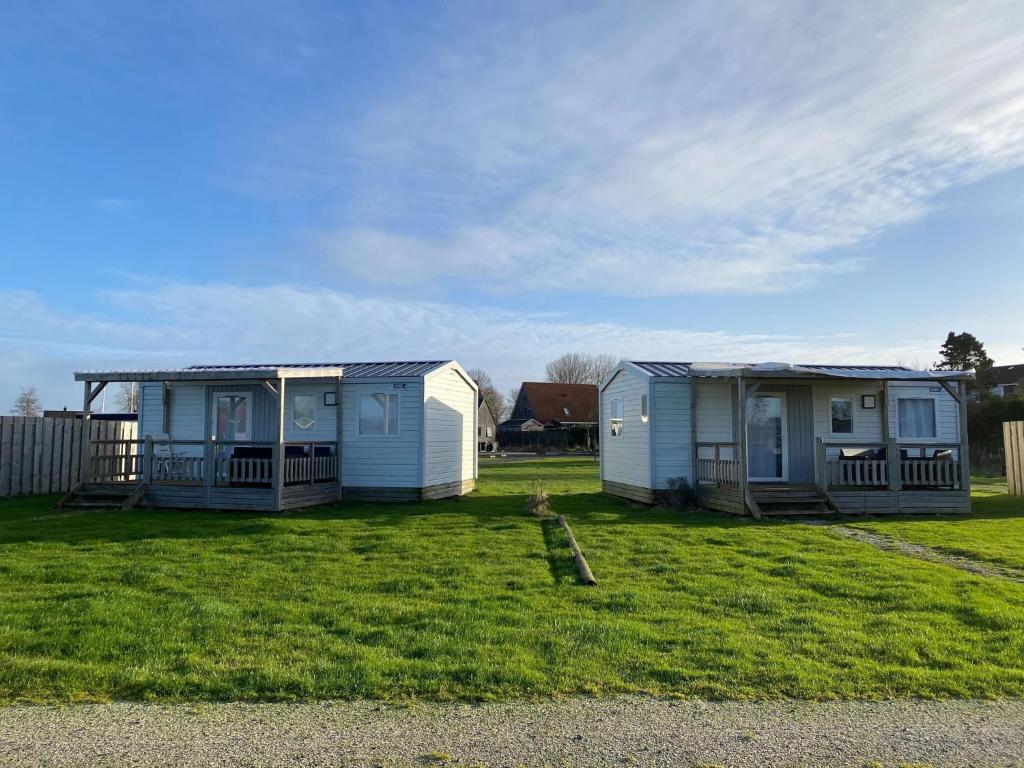 two mobile homes in a yard with grass at Compact 4 person chalet in Friesland in De Veenhoop