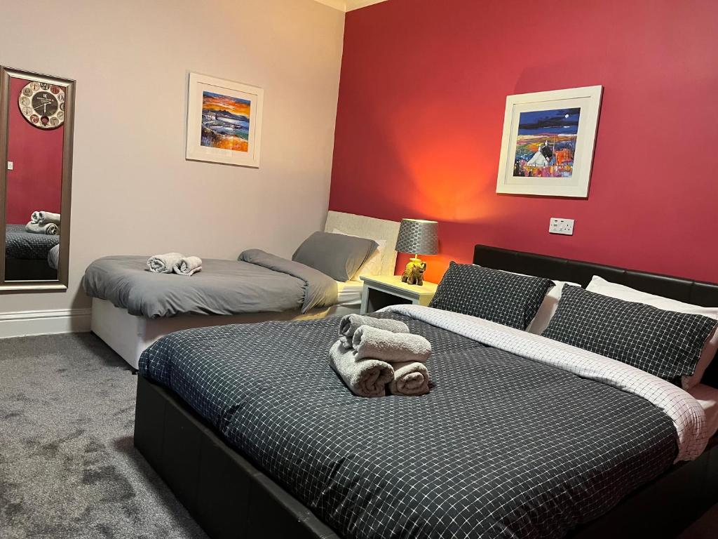a bedroom with two beds and a red wall at The waterfront in Tarbert