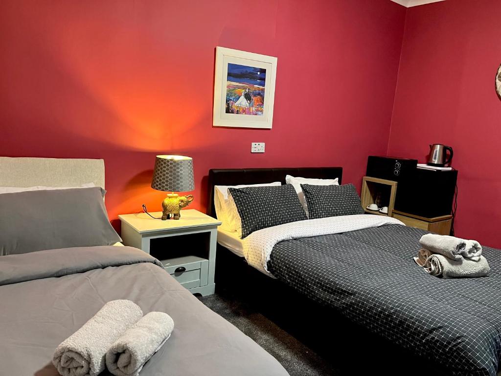 a bedroom with two beds and a red wall at The waterfront in Tarbert