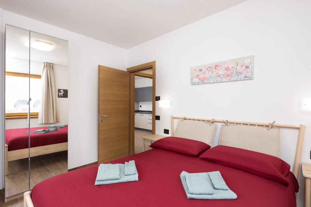 sypialnia z czerwonym łóżkiem i lustrem w obiekcie Pianeta Oro Chalet Allegra w Livigno