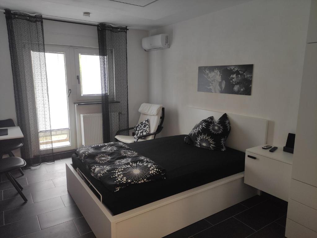 ein Schlafzimmer mit einem Bett und einem Stuhl darin in der Unterkunft Black & White Apartment in Saarbrücken