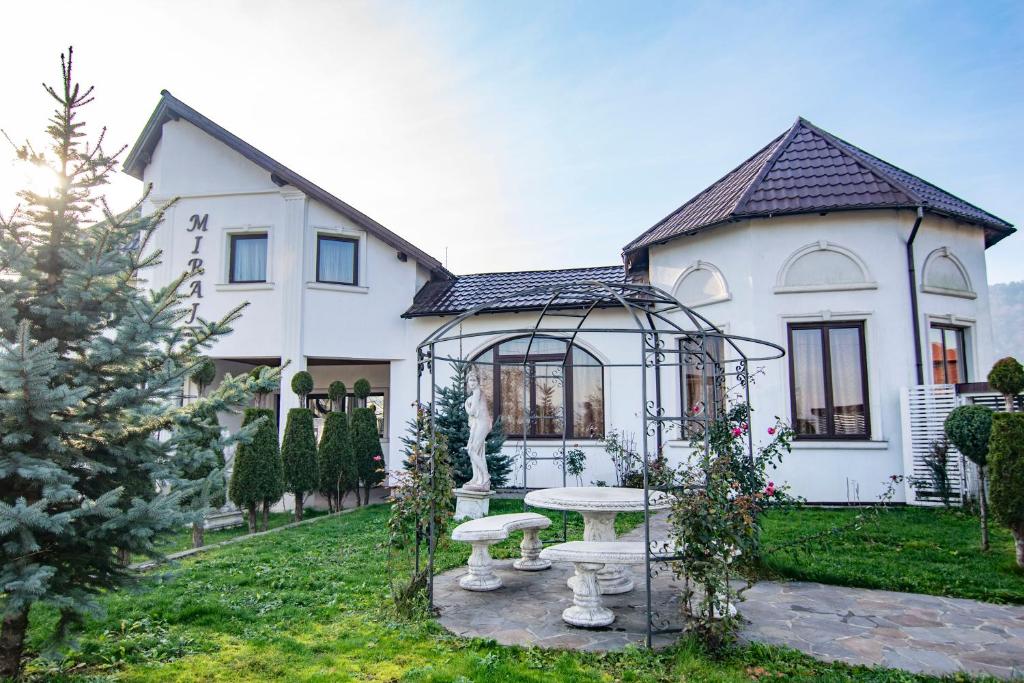 Uma casa branca com uma mesa de piquenique à frente. em Pensiunea Miraj em Sărăsău