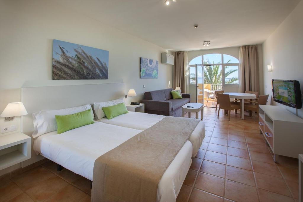 サンアグスティンにあるGrupotel Monte Felizのベッドルーム(大型ベッド1台付)、リビングルームが備わります。