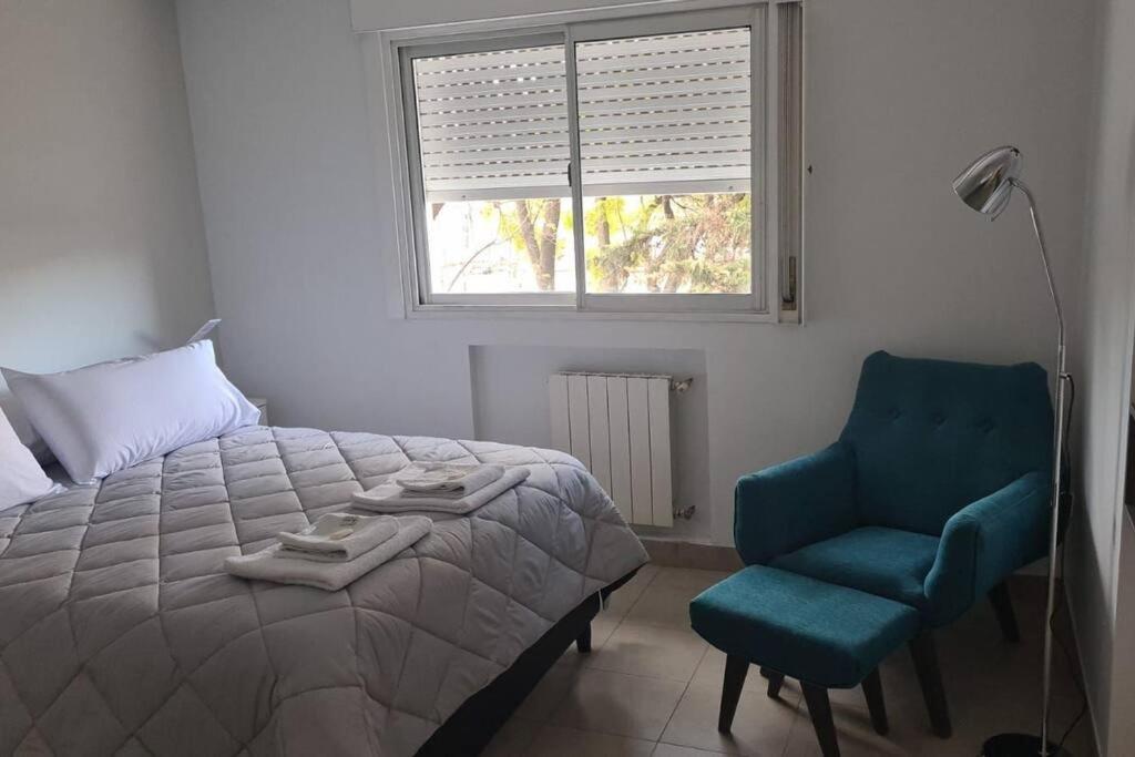 1 dormitorio con 1 cama, 1 silla y 1 ventana en Departamento con pileta, balcón y parrilla en Salta