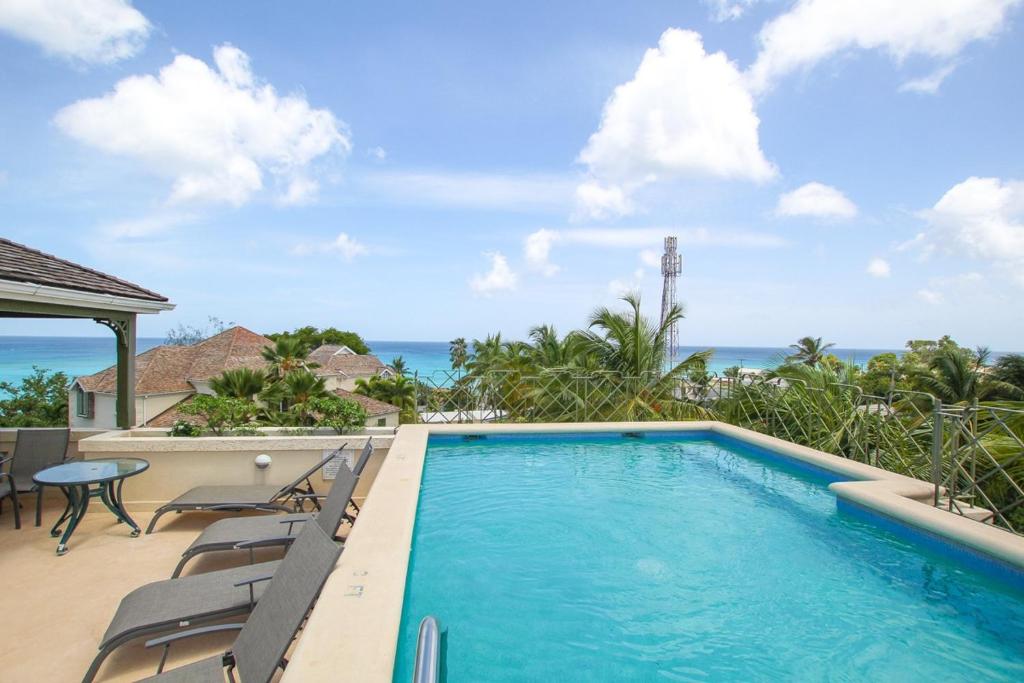 a swimming pool with chairs and the ocean in the background at Beacon Hill 304 by BSL Rentals in Saint Peter