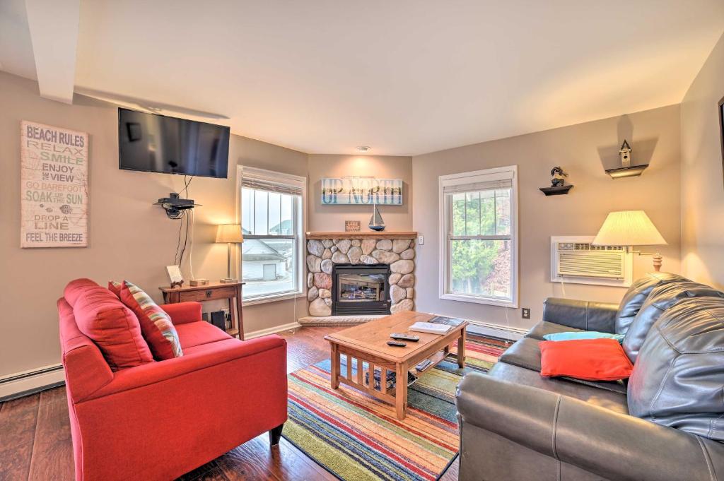 uma sala de estar com um sofá e uma lareira em Portage Lake Condo with Deck and Pool Access! em Onekama
