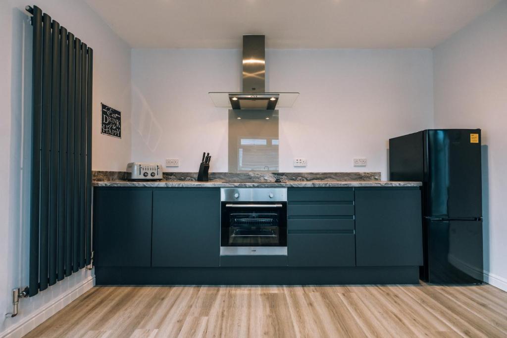 a kitchen with black cabinets and a black refrigerator at Wolviston House By Horizon Stays in Stockton-on-Tees
