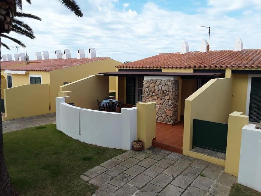 una casa con una valla blanca en un patio en Apartamento en Calan Blanes, Ciutadella, en Cala en Blanes