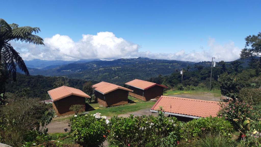 eine Gruppe von Hütten mit Bergen im Hintergrund in der Unterkunft Hotel Mirador de Quetzales in Providencia