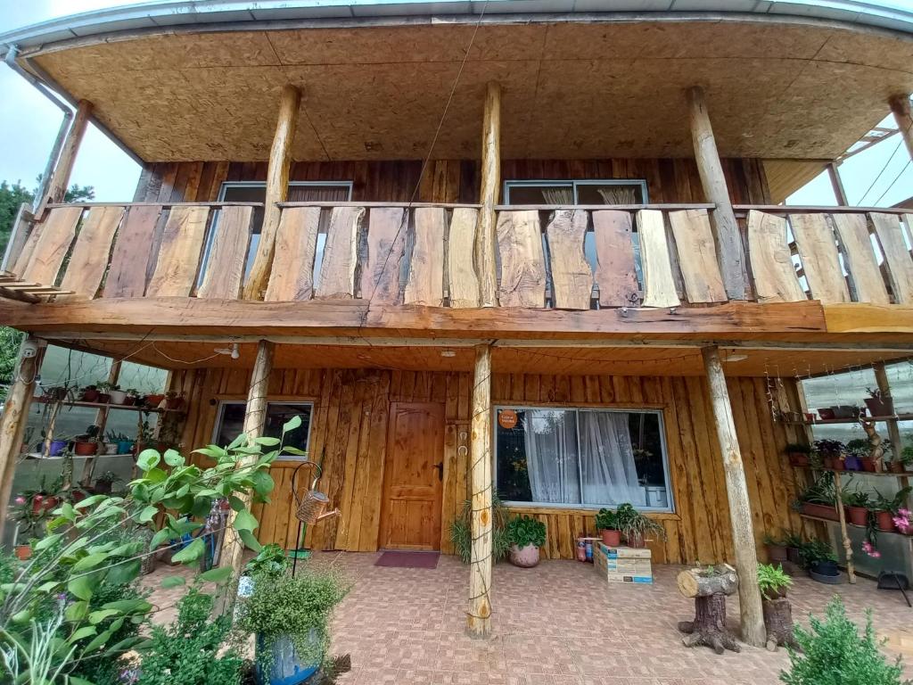Casa de madera con balcón en la parte superior. en Mercadito de Pamela, en Huépil
