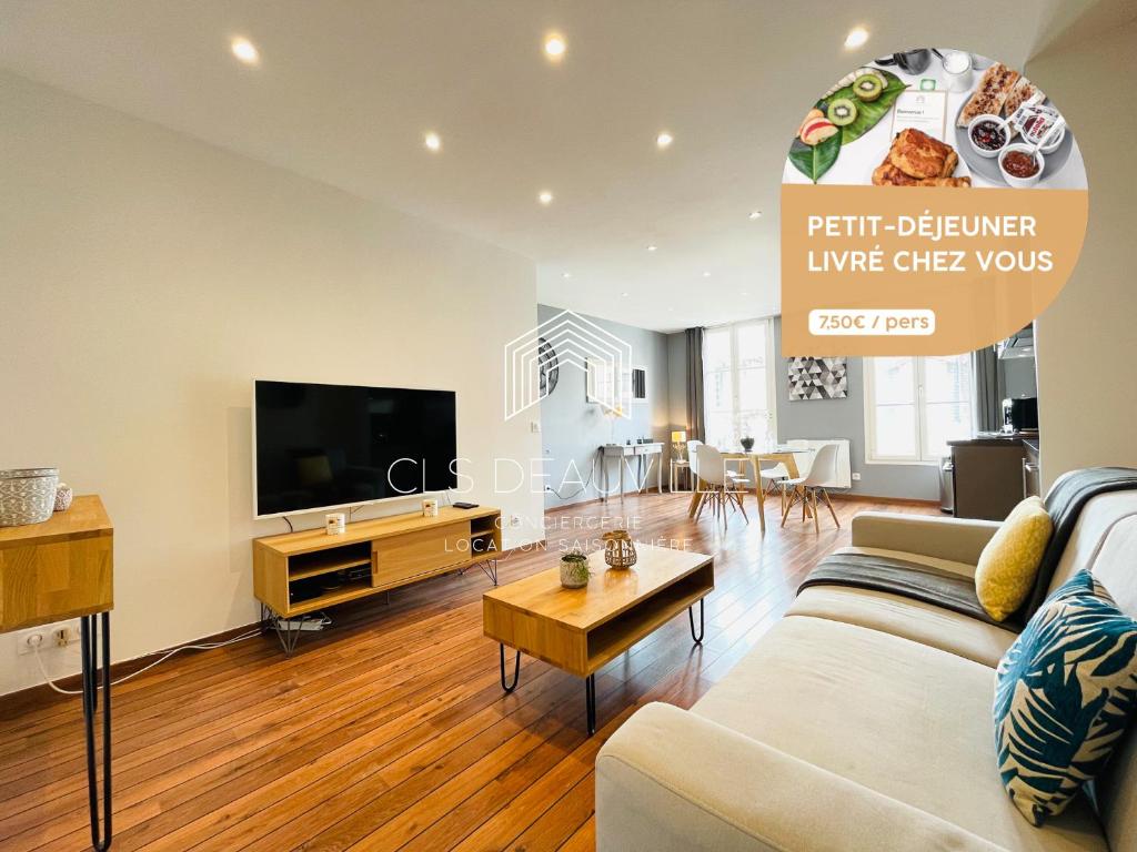 a living room with a couch and a tv at Appartement Coeur de Deauville in Deauville