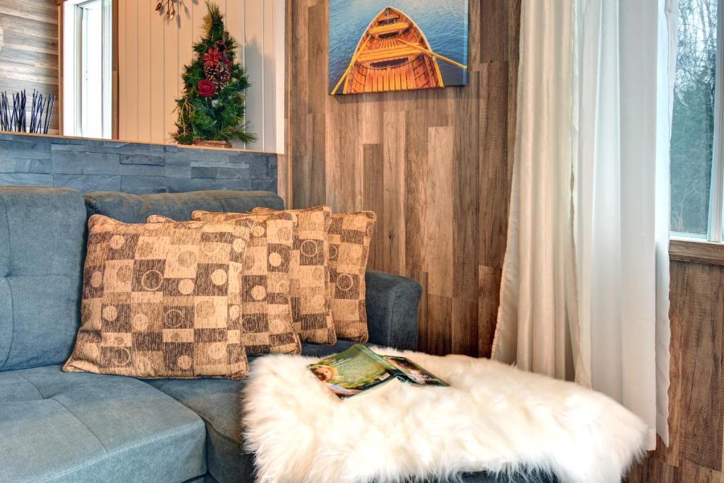 a living room with a blue couch with a furry pillow at Alison On Lake & Romantic Getaway With Private Hot Tub in Rivière-Rouge