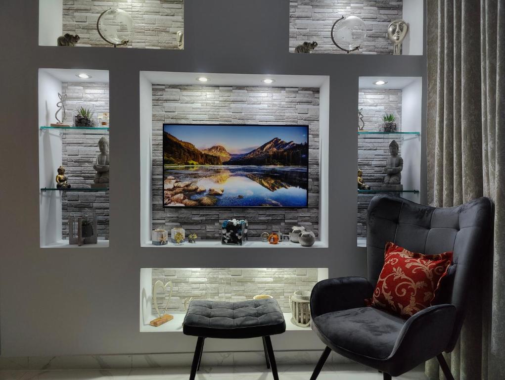 a room with a chair and a television on a wall at Cozy Sea View Apartment in Paralia in Paralia Katerinis
