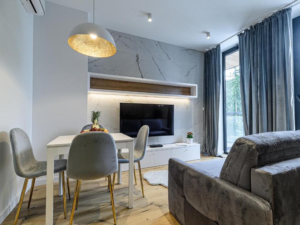 uma sala de estar com uma mesa e cadeiras e um sofá em VisitZakopane- Toscana Apartment em Zakopane