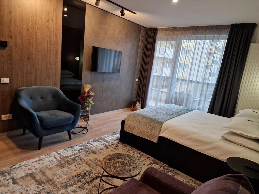 een slaapkamer met een bed, een stoel en een televisie bij AMA by Melis in Braşov