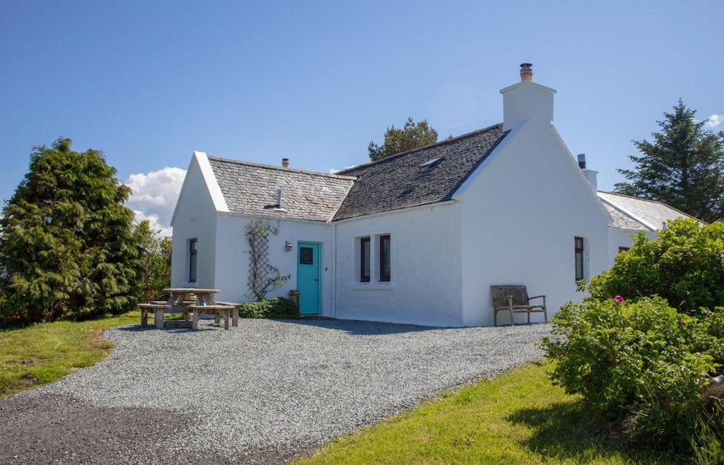 a white cottage with a picnic table in front of it at Ploughman's Cottage in Edinbain