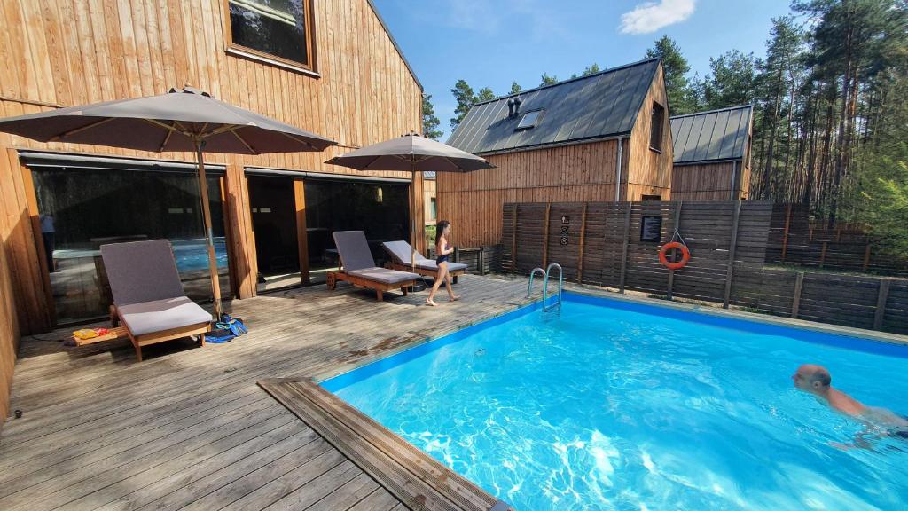 a swimming pool with a woman sitting on a deck at Osada Osjaków in Osjaków