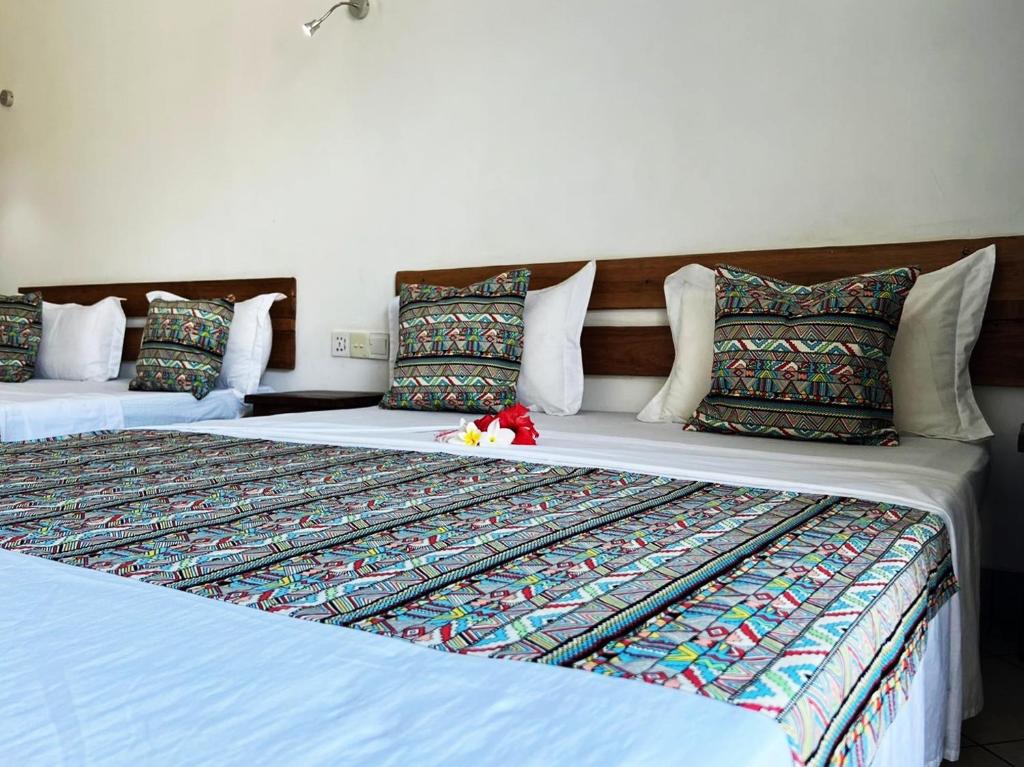 two beds sitting next to each other in a room at Hôtel Ambatoloaka in Nosy Be