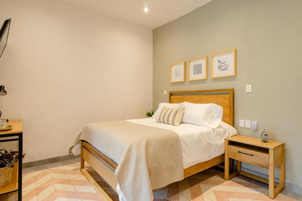 a bedroom with a bed with white sheets and a table at Casa Mateo in Guadalajara
