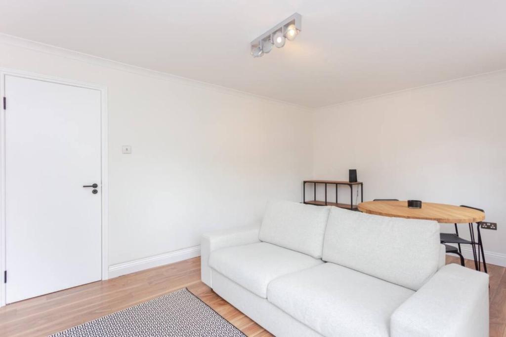 a white living room with a white couch and a table at Bright 2 Bedroom House in Stratford with Garden in London