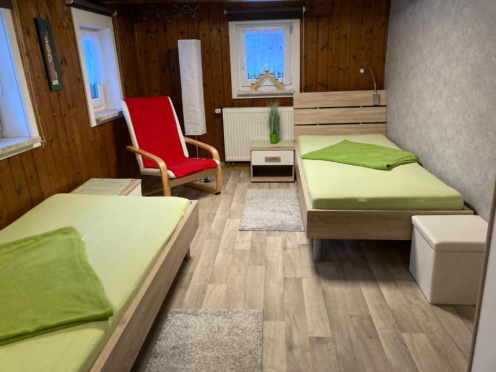 Zimmer mit 2 Betten und einem roten Stuhl in der Unterkunft Ferienhaus Tooren in Kurort Altenberg