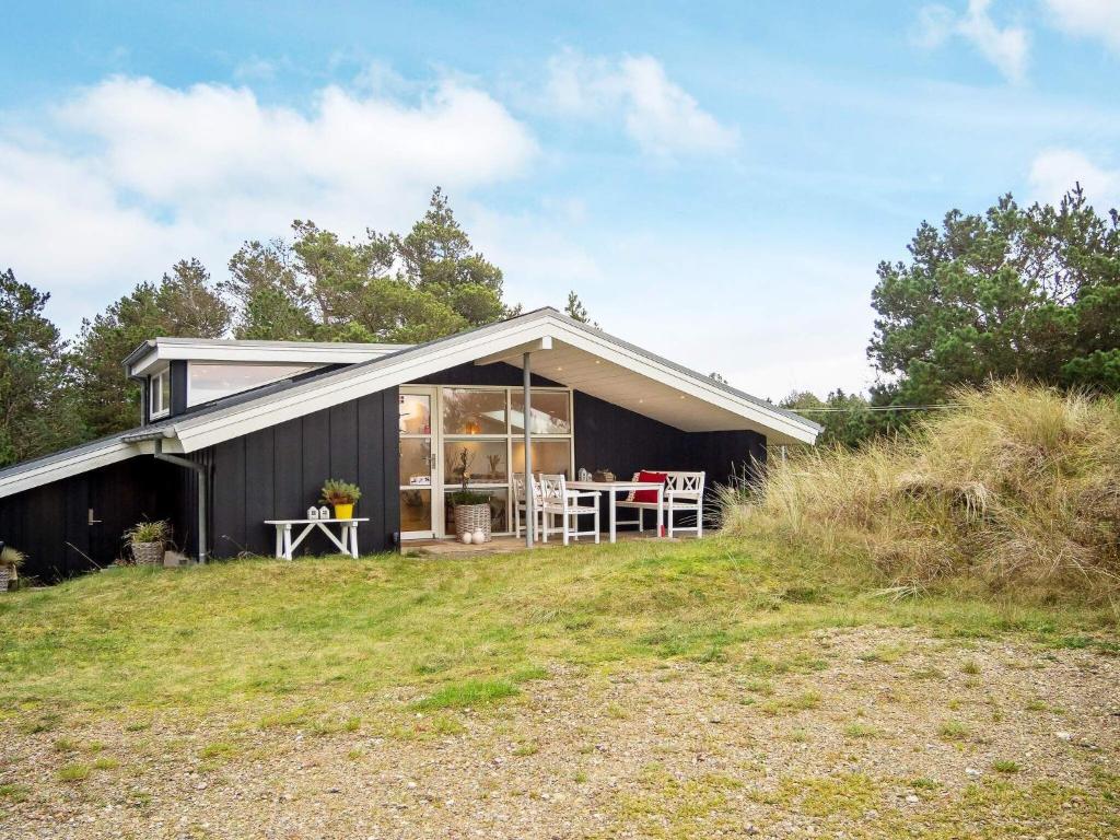 a black house with a table on a field at Holiday home Thisted LIII in Thisted