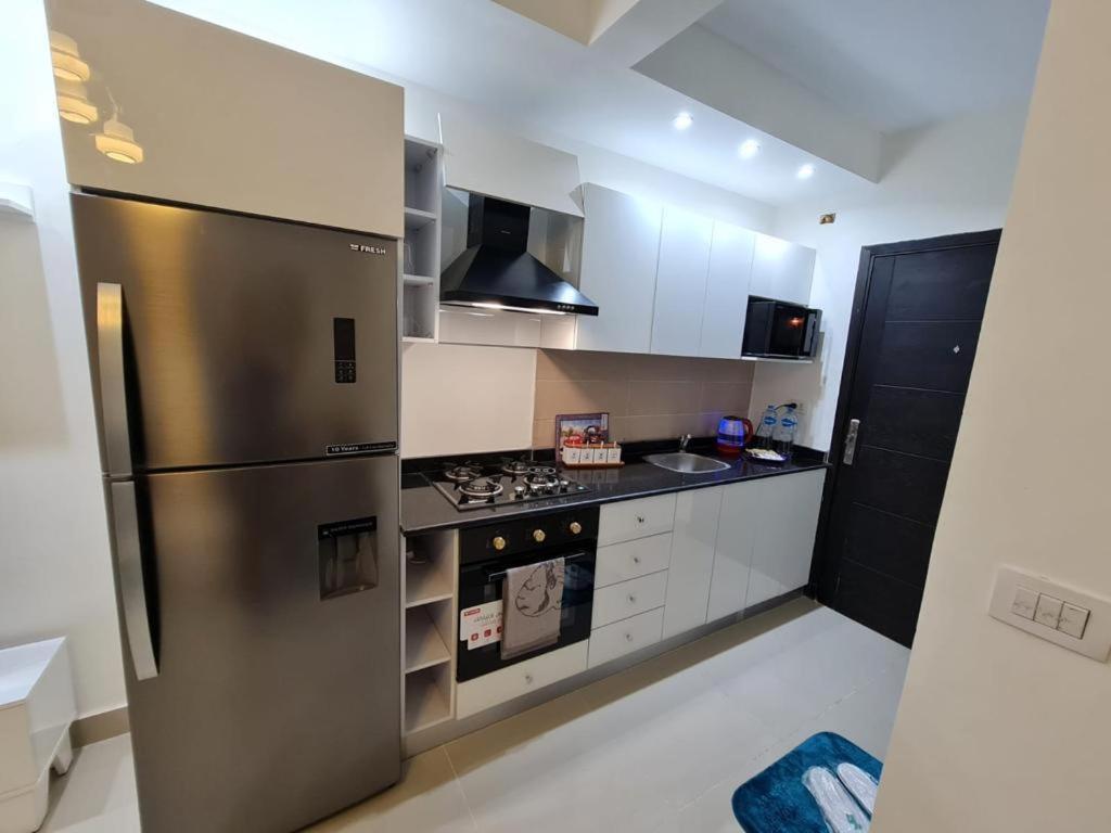 eine Küche mit einem Kühlschrank aus Edelstahl und weißen Schränken in der Unterkunft Diar El Rabwa Modern Apartment in Sharm El Sheikh
