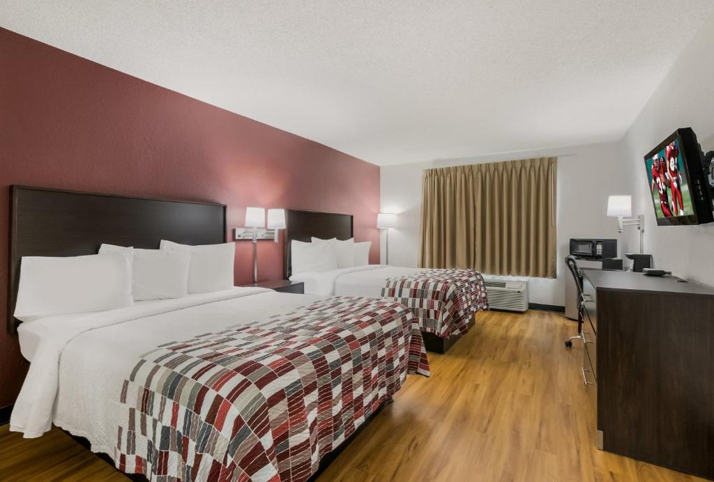 a hotel room with two beds and a desk at Red Roof Inn & Suites Knoxville East in Knoxville